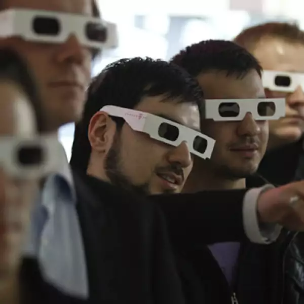 Varias personas utilizan lentes de 3-D para ver la presentación de Deutsche Telekom.