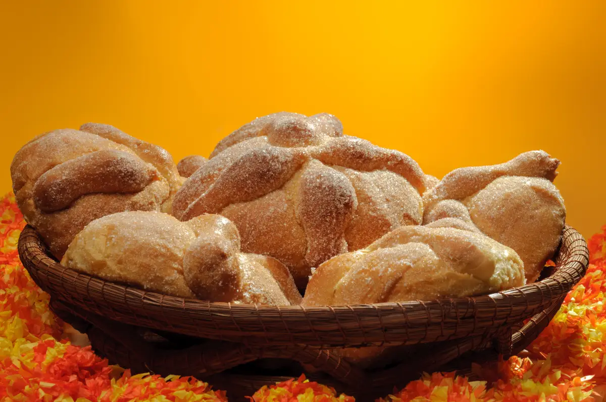 Pan de muerto en una canasta con un fondo naranja.
