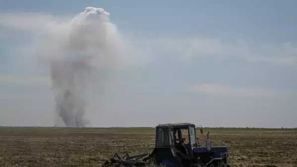 Un trabajador agrícola opera un tractor a medida que el humo aumenta en la distancia después de un ataque militar, en medio del ataque de Rusia contra Ucrania, en la región de Kherson, Ucrania, el 20 de junio de 2023.