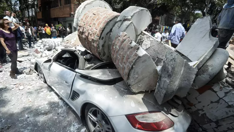 A car crushed by debris from a damaged building after a quake rattled