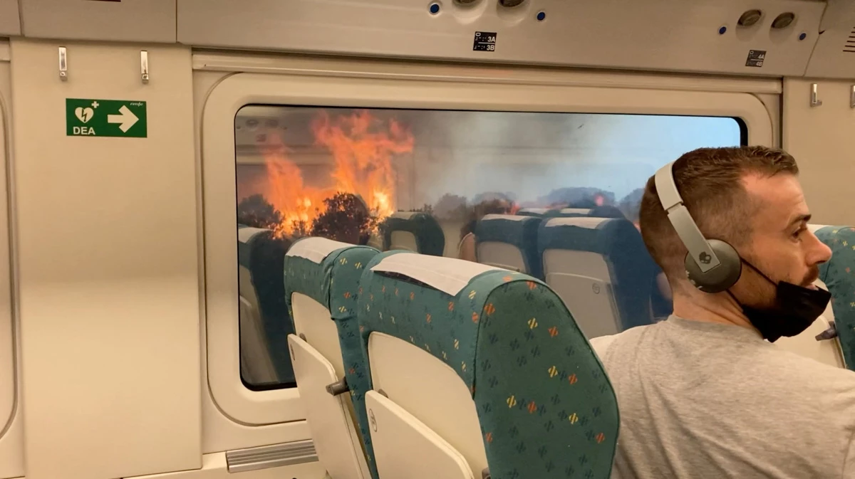 Pasajeros miran el incendio forestal desde un tren, cerca de Zamora, España, el 18 de julio de 2022, en esta captura de pantalla obtenida de un video de las redes sociales.