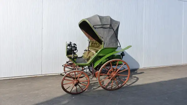 Flocken Elektrowagen, uno de los primeros automóviles eléctricos, con carrocería verde, ruedas de madera y diseño similar al de un carruaje.