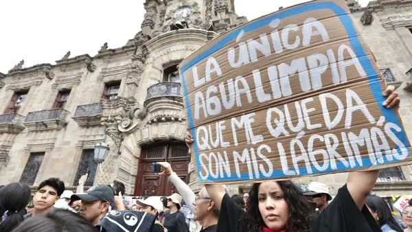En la imagen, una joven sostiene una pancarta con la frase "La única agua limpia que me queda son mis lágrimas".