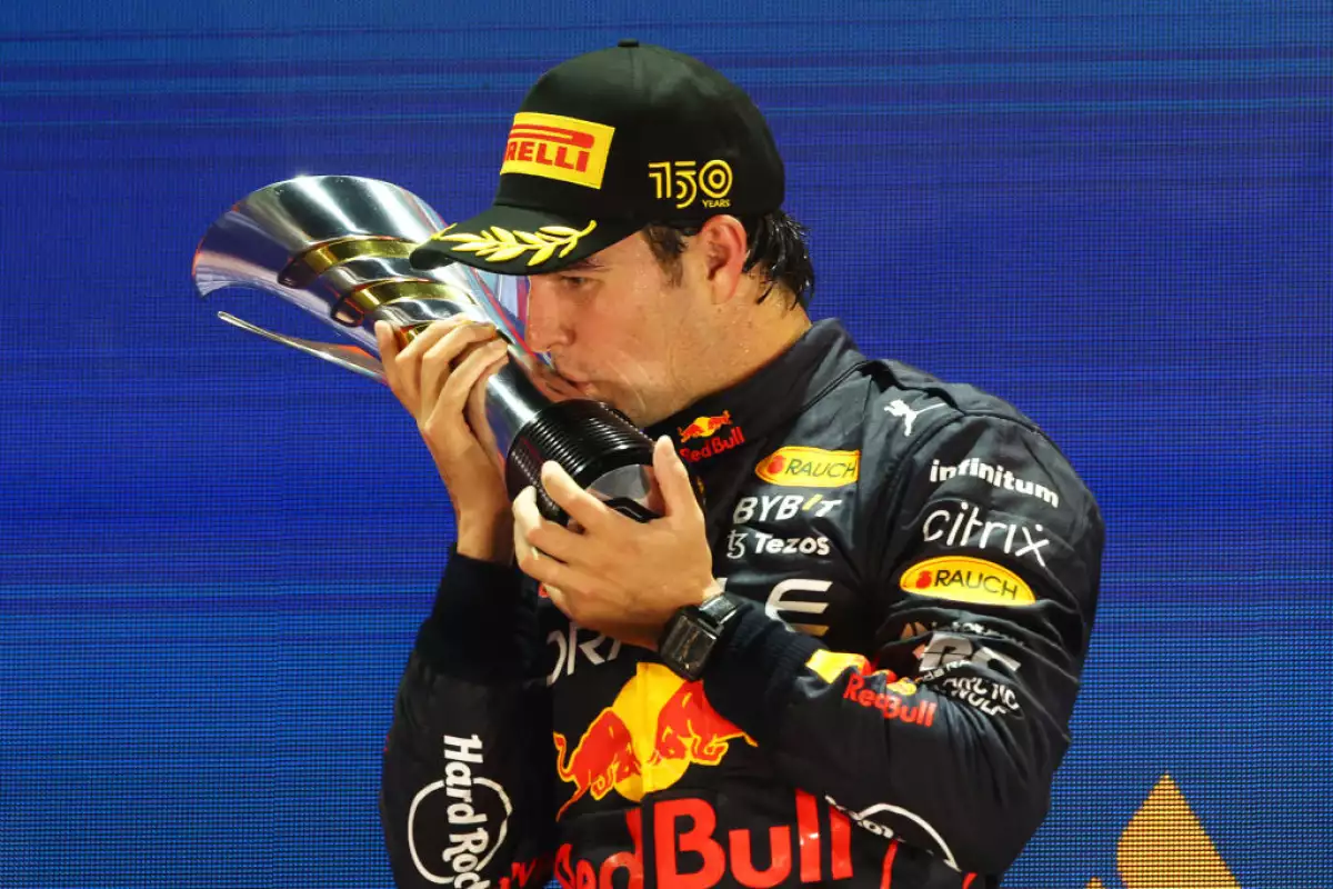 Foto de Checo Pérez besando el trofeo del Gran Premio de Singapur 2022 tras haber quedado en primer lugar de la carrera.