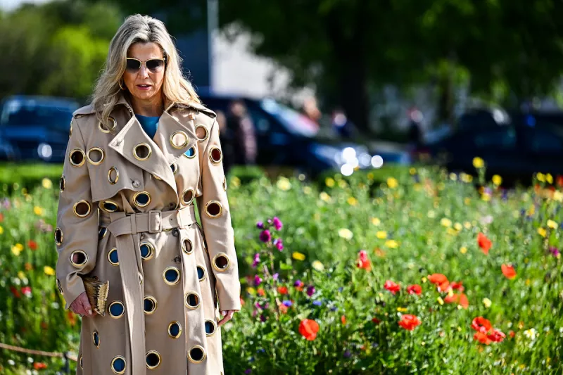 Máxima de holanda con un conjunto azul y una gabardina con múltiples agujeros. 