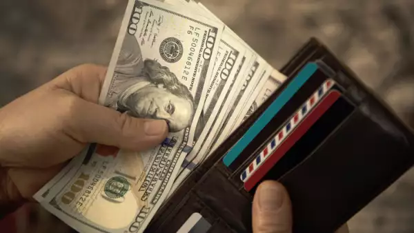 High angle view of unrecognizable mature man placing USA Dollar bills into wallet