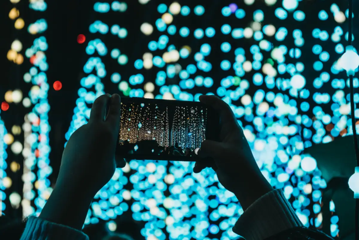 Hands holding mobile phone above head, taking photos.