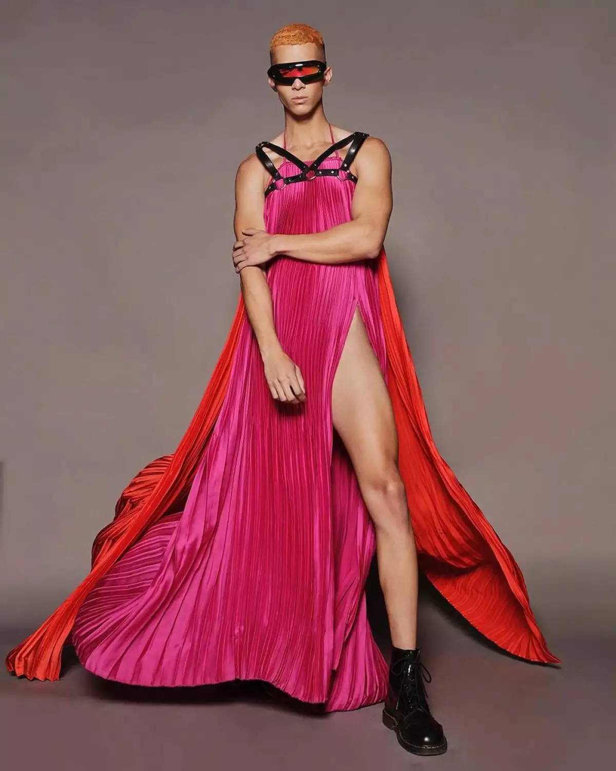 Persona posando con un vestido plisado de color rojo y naranja del diseñador mexicano Guillermo Jester. 