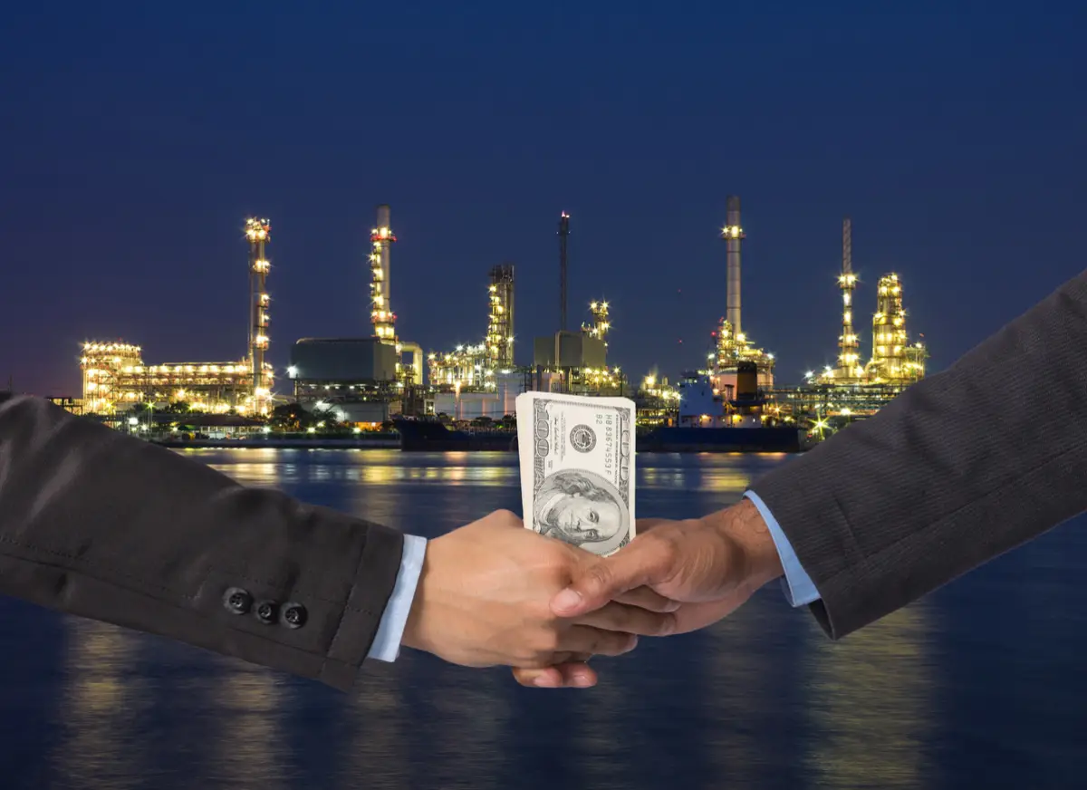 Hand shake between a businessman with dollar money on Petrochemi