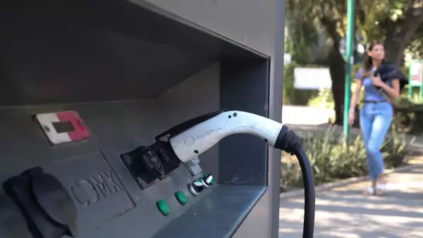 A woman walks past an electric vehicle charging station in Mexico City