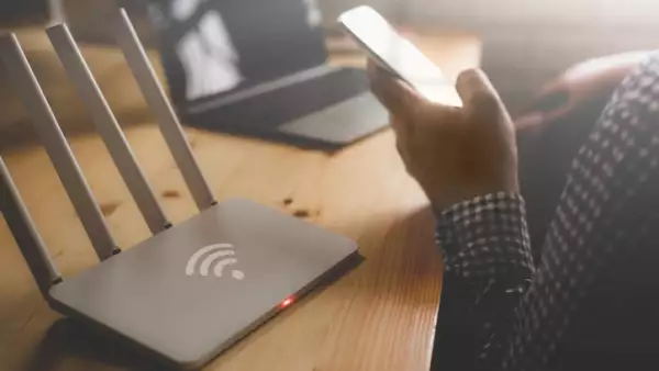 closeup of a wireless router and a man using smartphone on living room at home ofiice