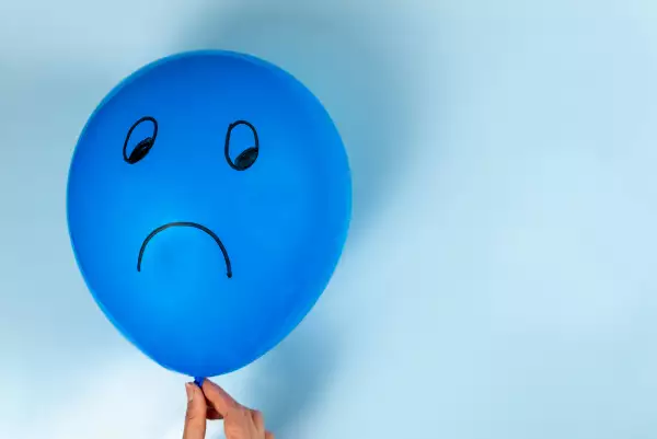 A sad Blue Monday emoticon is drawn on a hot air balloon on a blue background.