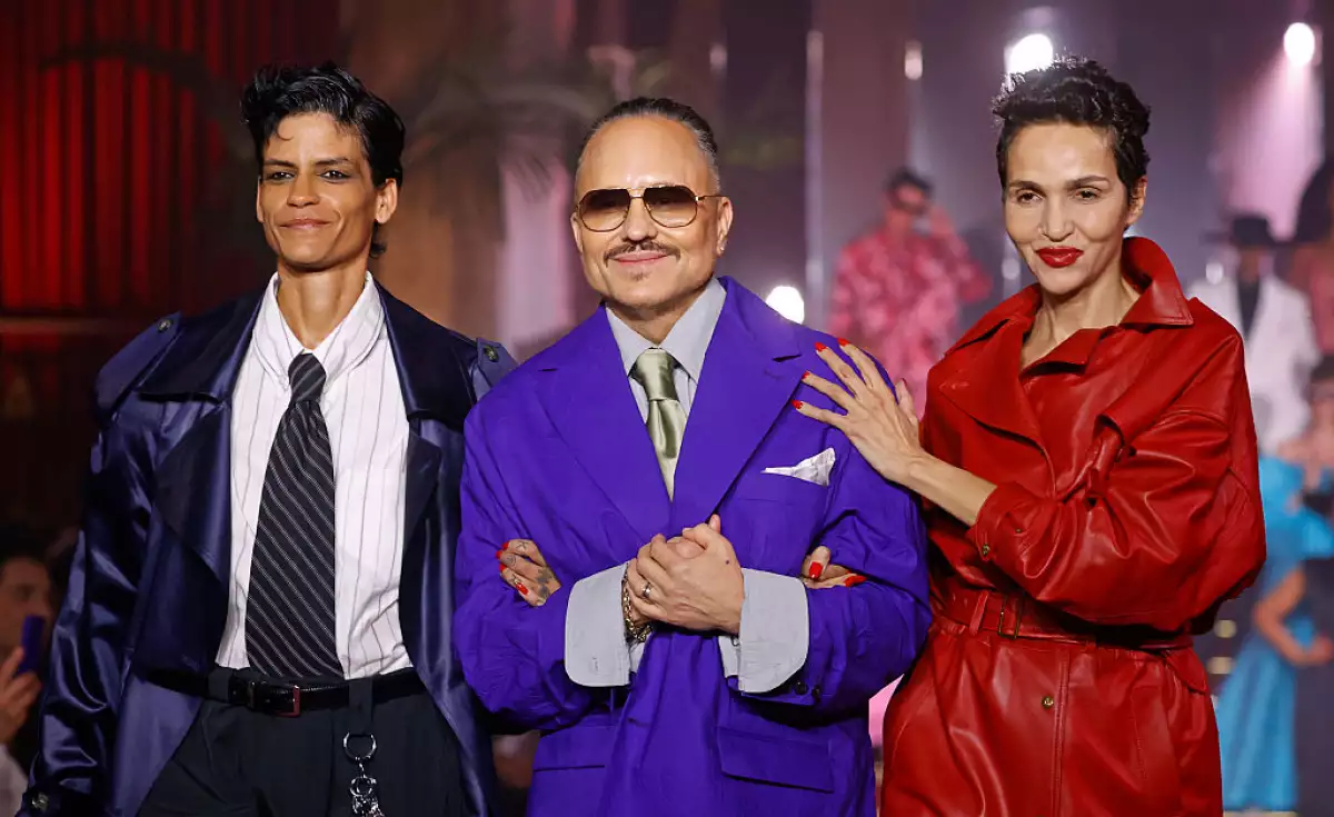 Foto de Willy Chavarría con un saco over sized púrpura y corbata plateada, caminando por la pasarela de París Fashion Week.