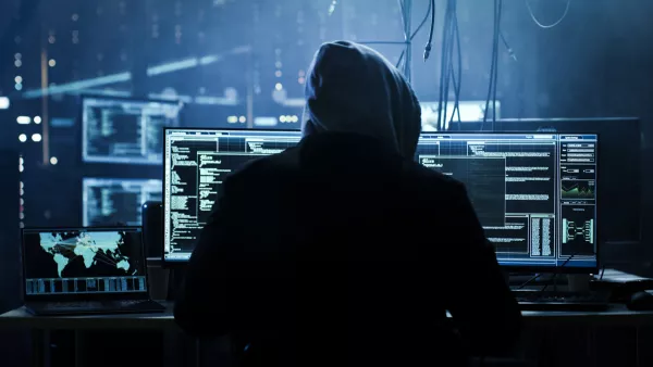 Dangerous Hooded Hacker Breaks into Government Data Servers and Infects Their System with a  Virus. His Hideout Place has Dark Atmosphere, Multiple Displays, Cables Everywhere.
