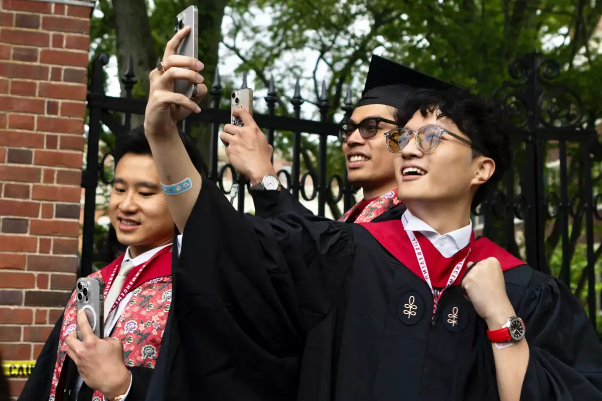 Los estudiantes de graduación toman fotos de sus compañeros en Harvard Yard el 28 de mayo de 2025 en Cambridge, Massachusetts. La ceremonia tiene lugar mientras Harvard se enfrenta a una renovada presión política, con la administración Trump para cancelar contratos federales por un total de alrededor de 100 millones de dólares.