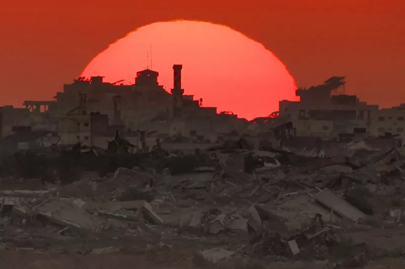 Esta imagen tomada desde una posición en la frontera israelí con la Franja de Gaza, muestra la puesta de sol detrás de edificios destruidos en el territorio palestino sitiado el 19 de agosto de 2025.