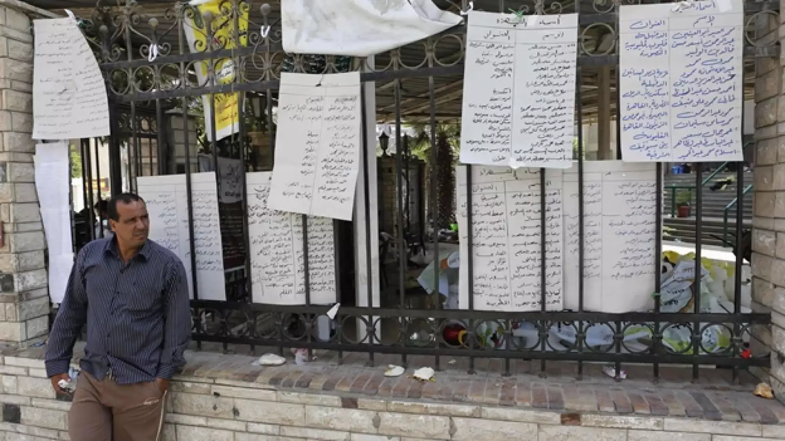 un hombre parado junto a una lista de nombres de muertos en manifestaciones