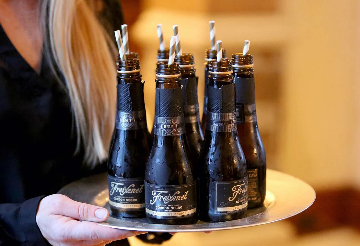 Freixenet México apuesta al turismo para vender vino (Botellas de Freixenet en una bandeja que sostiene una mesera)