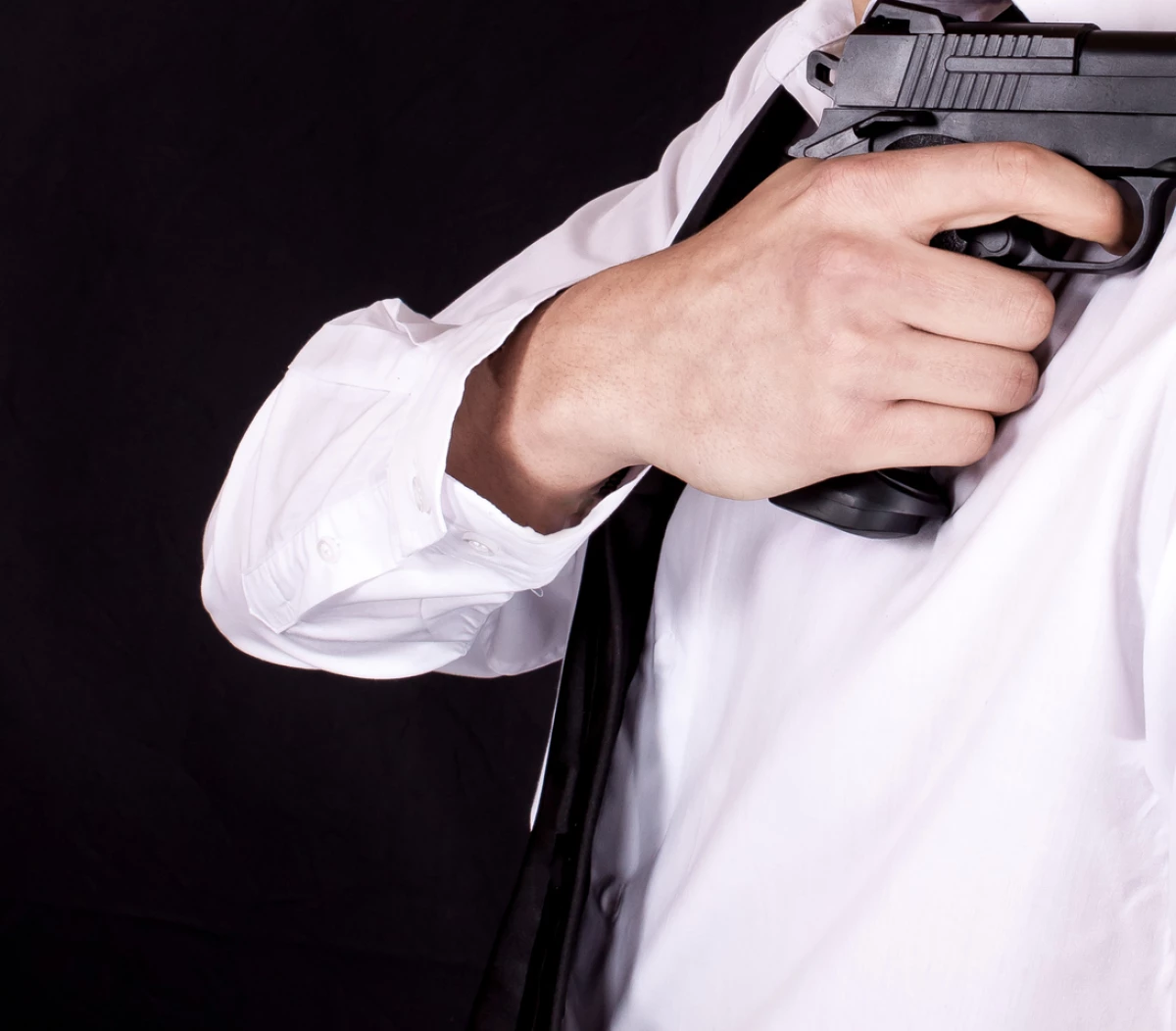 Man in black suit holding gun in hand. Secret agent, mafia, bodyguard concept.