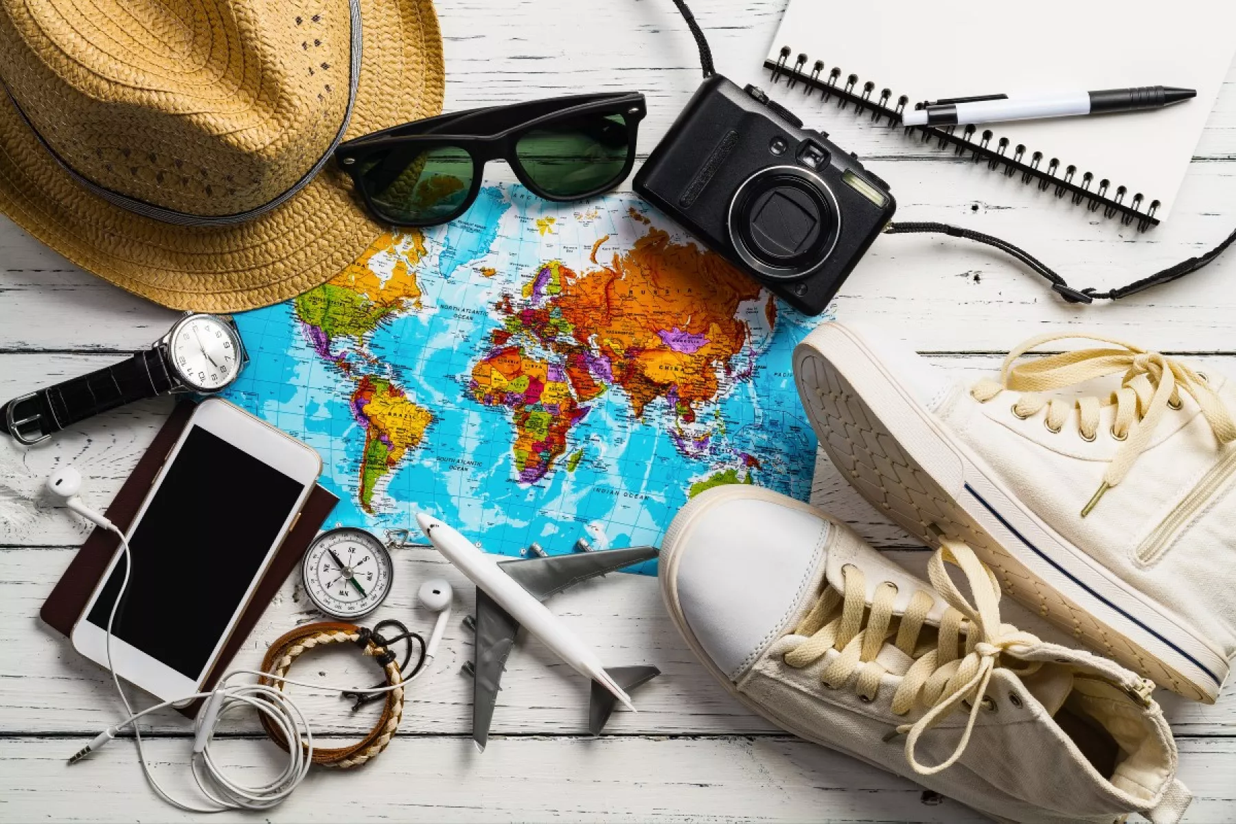 Artículos de viaje necesarios, tenis, celular, lentes de sol, cámara, sombrero, audifonos.