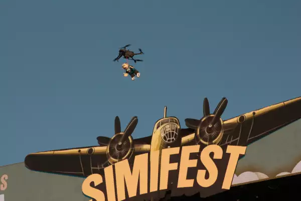 Foto de un peluche de Dr. Simi volando colgado de un dron.