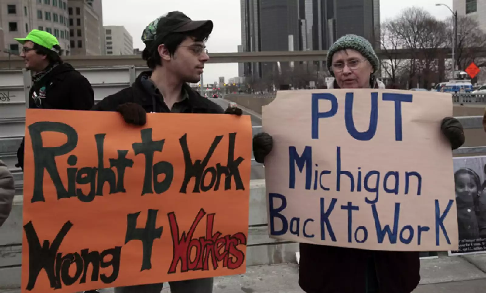 Dos manifestantes con mantas en una protesta por los derechos de los trabajadores, frente a la sede del evento.