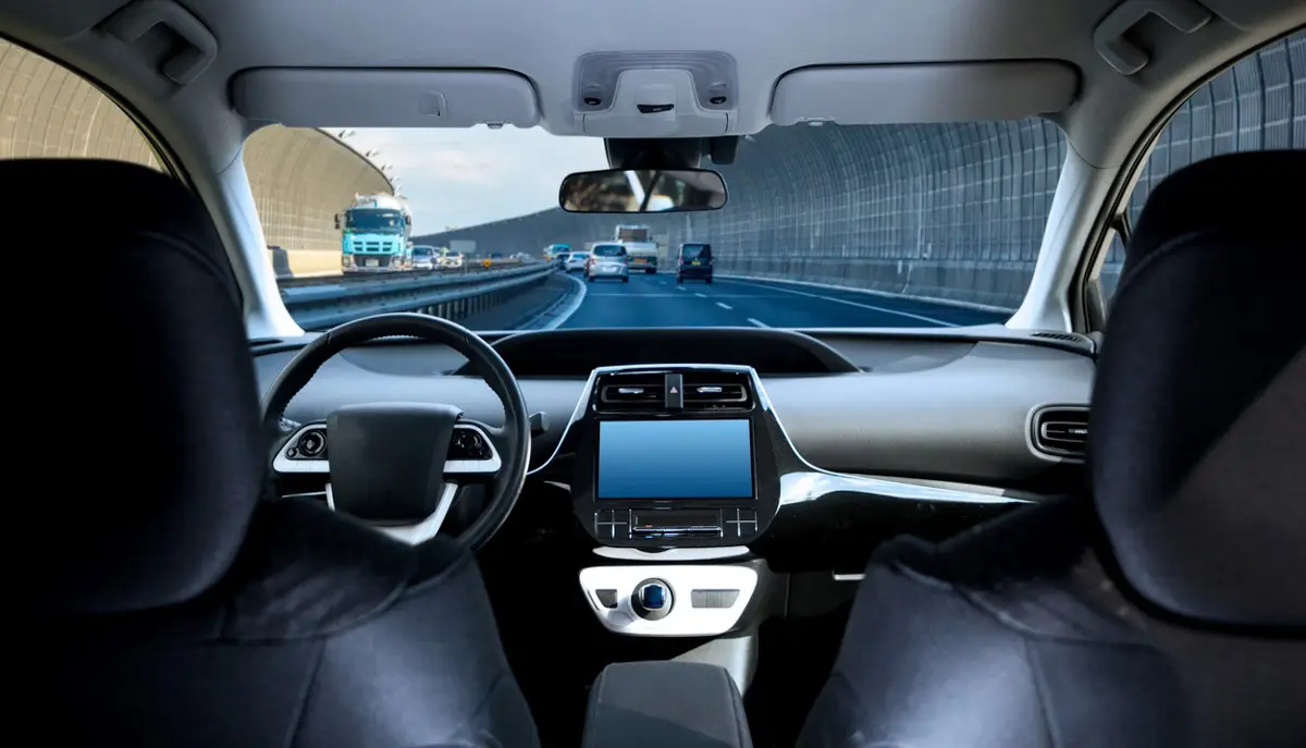 Cockpit of driverless car driving on highway viewed from rear seat.