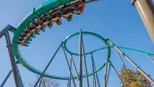 Montaña rusa Goliath de Six Flags con pasajeros recorriendo una curva elevada bajo un cielo despejado.