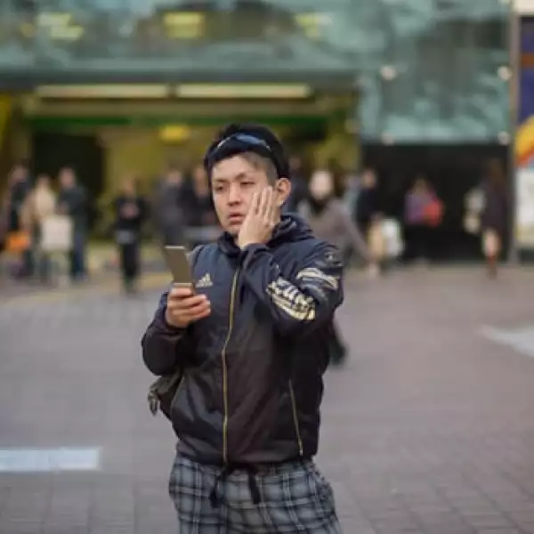 un joven ve su celular en tokio