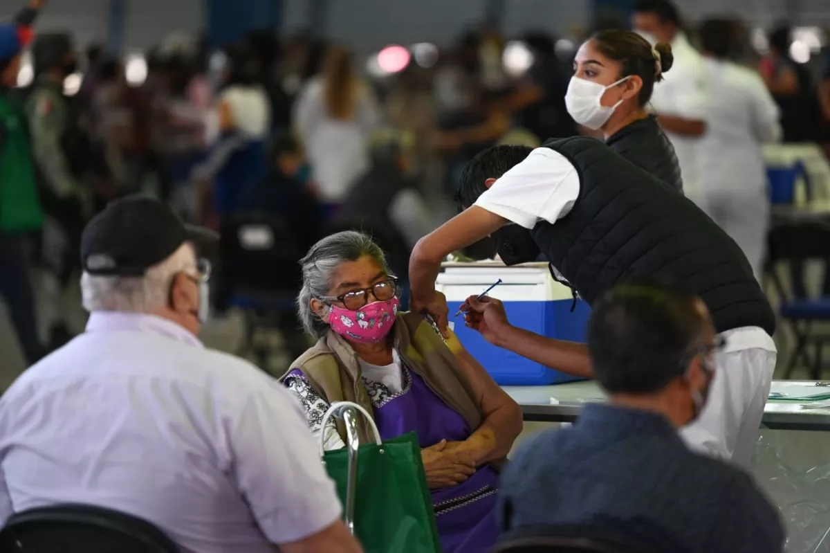Una adulta mayor es vacunada contra el Covid-19 dentro del Palacio de los Deportes.