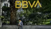 BBVA Spark inicia operaciones en México (Una mujer revisa su teléfono debajo de un anuncio de la marca)