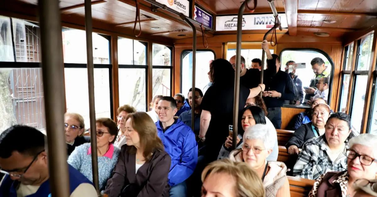 Interior de un tranvía en donde viajan 14 personas sentadas y cuatro paradas. El color del tranvía es café.jpg