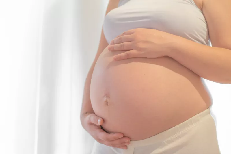 Pregnant woman with hand on belly.