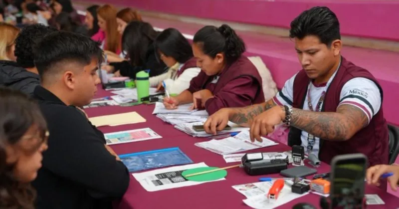 Seis mujeres y tres hombres sentados alrededor de una mesa color vino, en medio hay papeles, folders y plumas.jpg