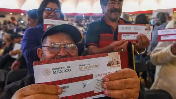 Adultos mayores sostienen un sobre de Programas del Bienestar.