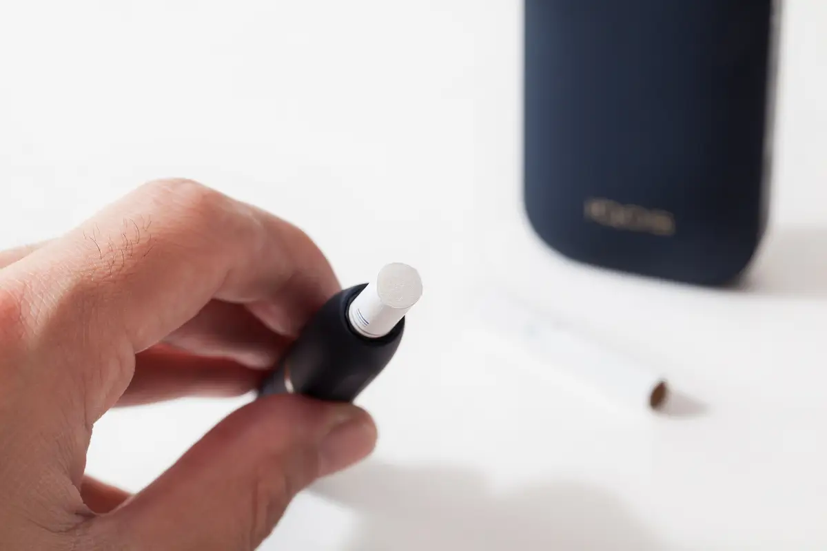 Acercamiento a una mano que sostiene un dispositvo IQOS