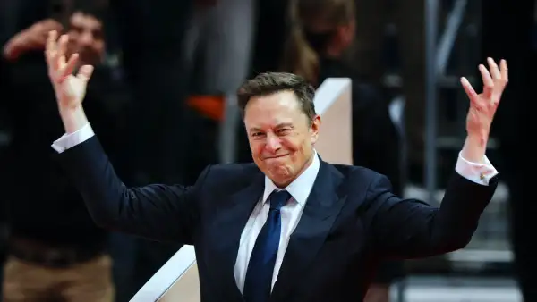 Elon Musk en primer plano con un gesto animoso y las manos levantadas como para animar a su audiencia.