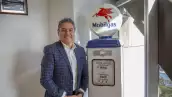 Foto de Alejandro García, director de Marketing para el negocio de combustibles de ExxonMobil en México, posando ante una replica de una bomba despachadora de gasolina antigua con logos de la marca.