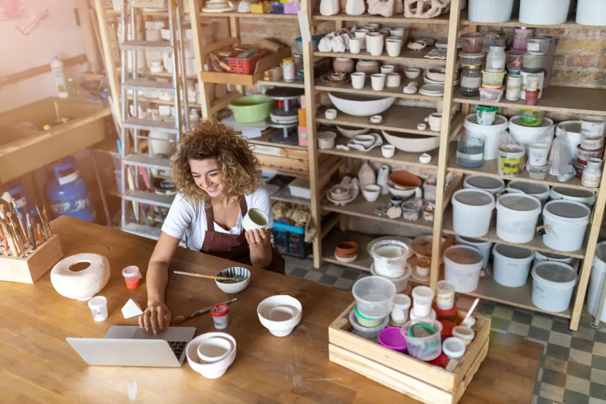 Female potter using laptop in art studio