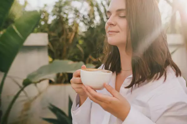 Mujer disfrutando el olor de su café 

