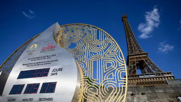 Foto en primer plano del reloj Omega Olympic que lleva la cuenta regresiva para los Juegos Olímpicos 2024, mientras que detrás se alcanza a ver la Torre Eiffel.