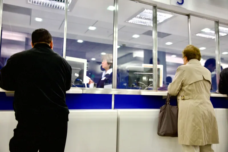 Personas reciben atención en ventanillas de un banco.