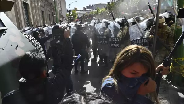 Una mujer se aleja del gas lacrimógeno disparado por las tropas militares fuera del Palacio Quemado en la Plaza Murillo en La Paz el 26 de junio de 2024.