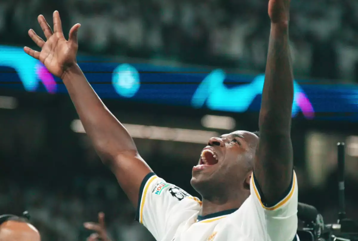 Foto de Vinicius Jr levantando los brazos al cielo emocionado durante un partido del Real Madrid.