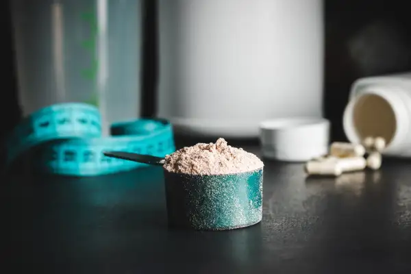 Chocolate,Whey,Protein,Powder,In,Measuring,Spoon,,White,Capsules,Of