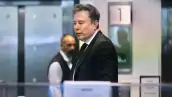 Elon Musk camina por el interior de un edificio mientras viste un traje negro y corbata.