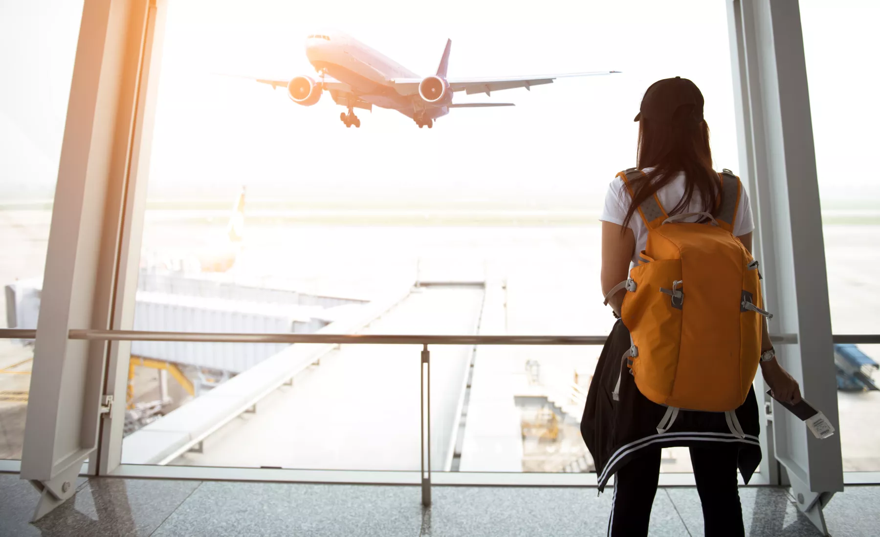 Una joven mira a través de la ventana mientras espera su vuelo en el aeropuerto, mismo que compró en el Hot Sale.