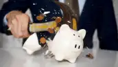 Una persona rompe una alcancía y salen disparadas unas cuantas monedas.
