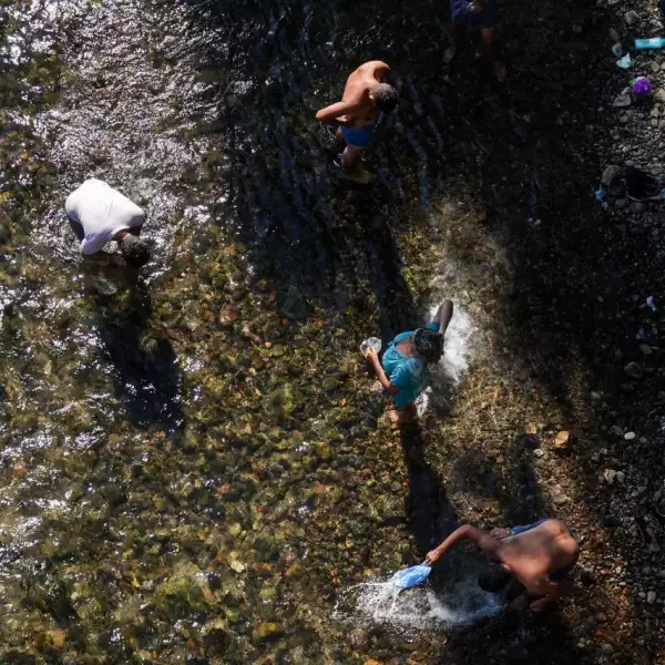 Migrantes toman un baño en el Río Ostuta previo a continuar su recorrido a Santiago Niltepec.