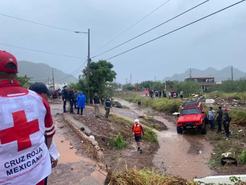 En la imagen se observa a elementos de la Cruz Roja Mexicana y de otras instituciones que realizan labores de atención a emergencias en Sonora, donde las fuertes lluvias del 30 y 31 de octubre dejaron encharcamientos. También hay un jeep rojo varado.